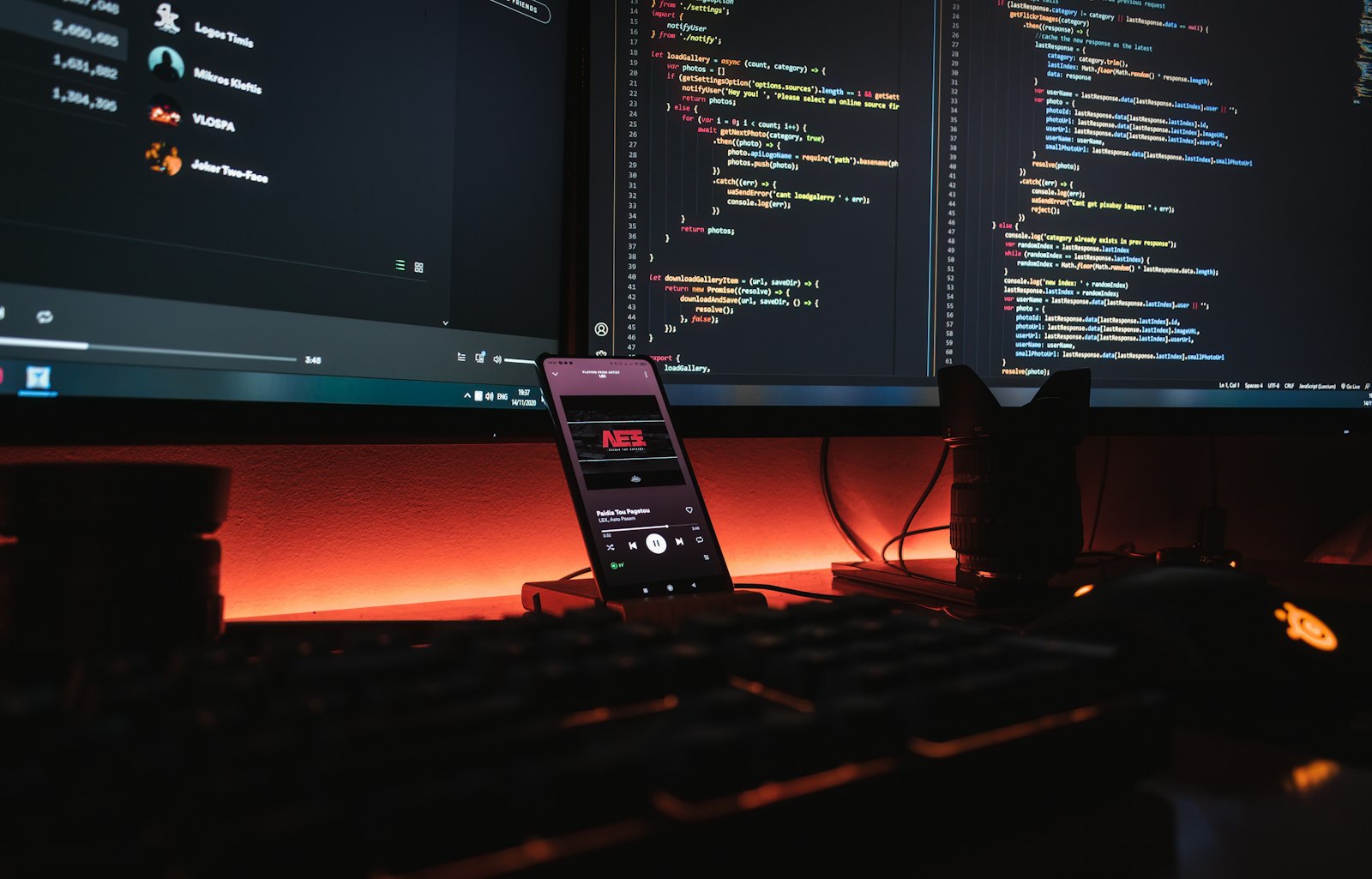 The Venture studio desk at night, website code on screen and a camera lens at hand